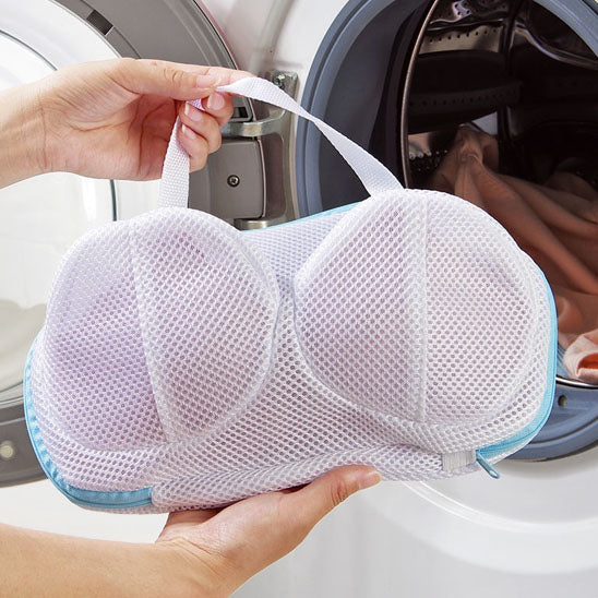 La photo montre un filet de lavage pour soutien-gorge prêt à être déposé dans la machine à laver.