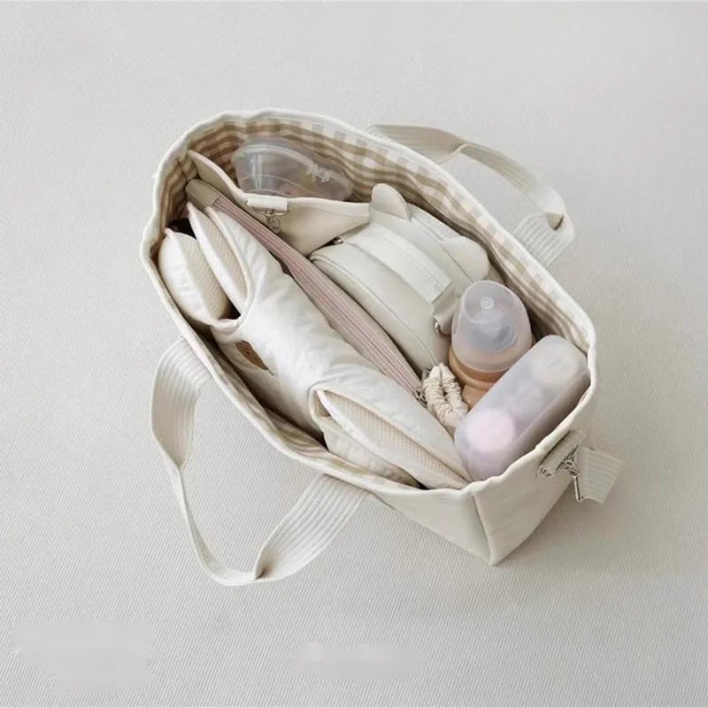 La photo montre un sac à langer vu de dessus avec tout le nécessaire pour bébé à l&