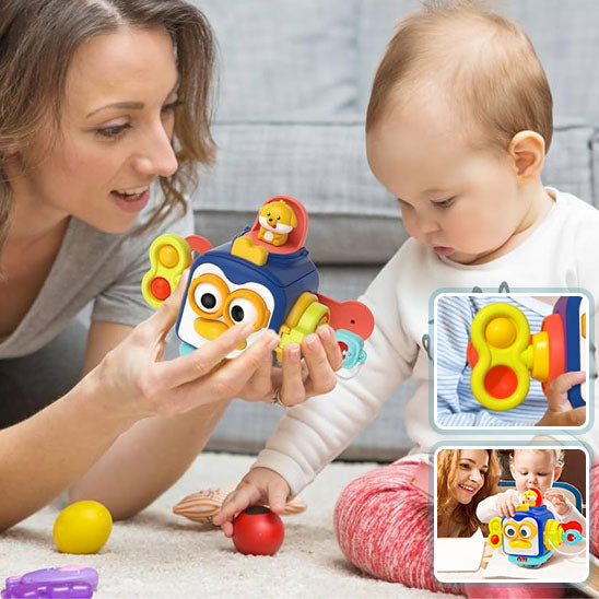 La photo montre un bébé avec sa maman qui tient ans sa main un jouet cube de la marque Montessori.