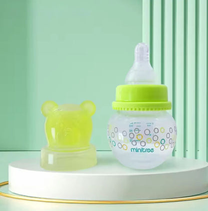 Baby bottles, specifically wide-bore PP bottles with bear-shaped caps, available in light-green