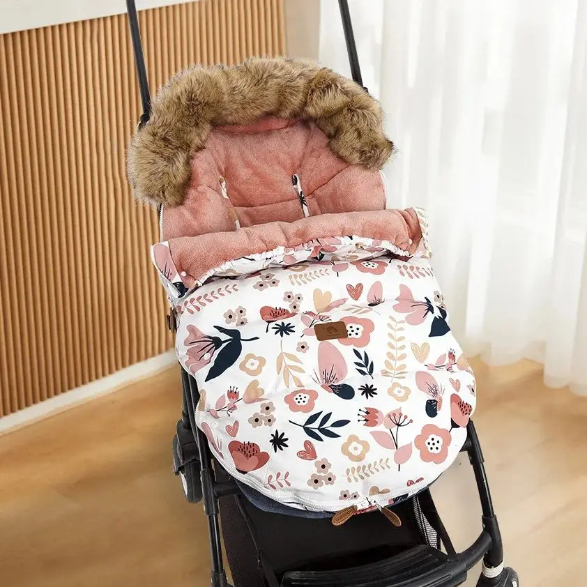 La photo montre une magnifique chancelière pour poussette aux motifs fleuris avec une capuche en fourrure .