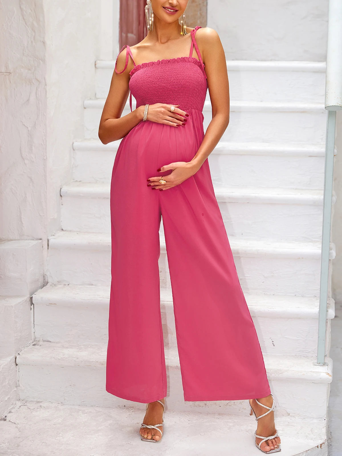 La photo montre une femme enceinte habillée d'une combinaison de maternité rose.