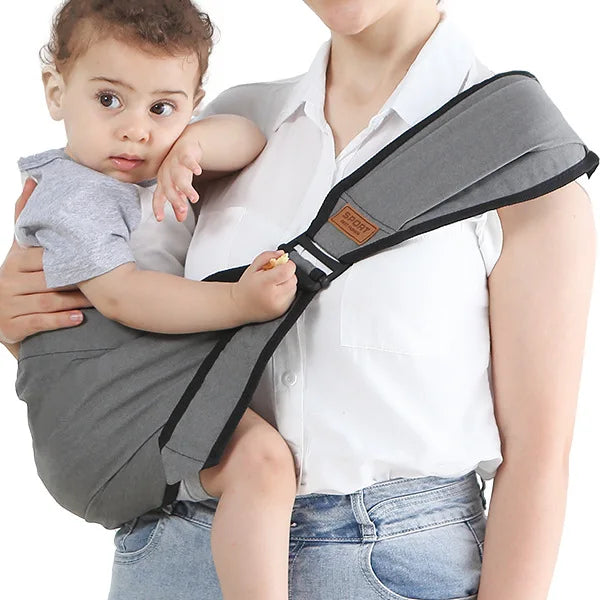 Photo montrant une maman avec son bébé en bandoulière dans un porte-bébé gris.