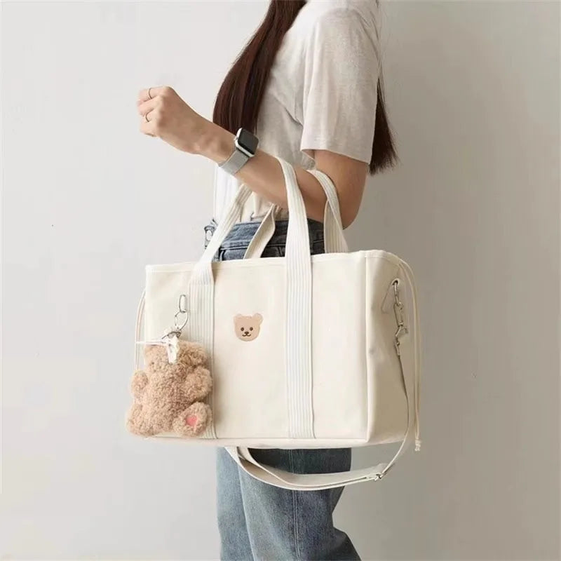 La photo montre une maman qui porte son sac à langer blanc décoré d'un ourson.