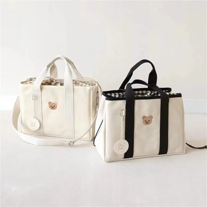 La photo montre deux sacs à langer, l'un avec des bretelles blanches et l'autre avec des bretelles noires.